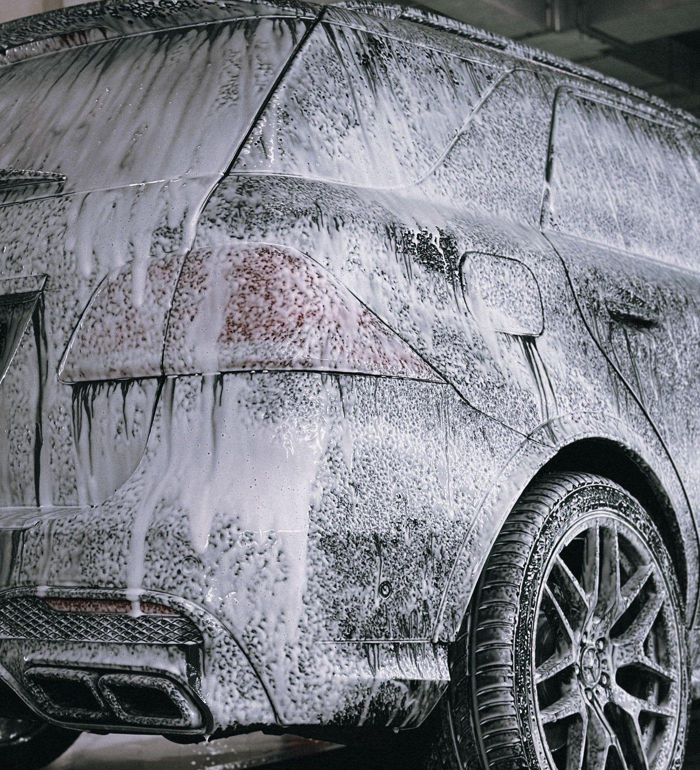 Car silhouette being hand washed with water droplets and a ceramic coating shield pattern