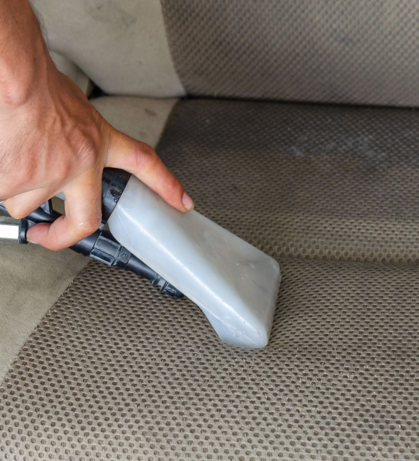 Car seat and dashboard being vacuumed and wiped down during an interior detail